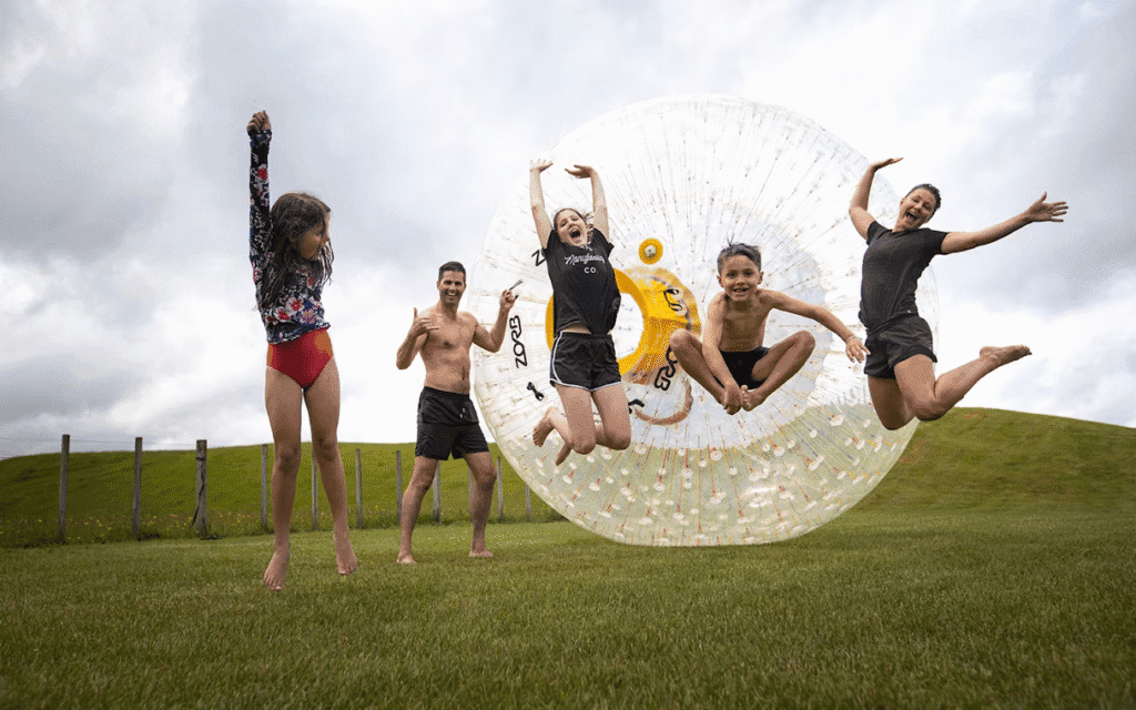 Some people rolling downhill inside a giant inflatable ball during a zorbing activity, one of the most unusual sports in the world.