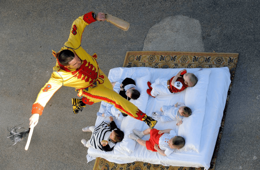 Man in devil costume jumping over infants at the Festival of Jumping Babies in Castrillo de Murcia, Spain